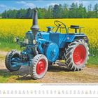 „APRIL“ steht groß unten links. Ein blauer Traktor steht vor einem gelben Feld. Am Horizont ist Wald zu sehen.