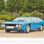 Text: "Der Lamborghini Espada ist ein viersitziges Coupé...APRIL 01 02 03 04..."  
Ein blauer Oldtimer vor einer grünen Landschaft und Bäumen.