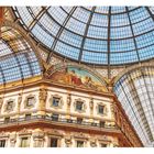 Ein Gemälde unter einer beeindruckenden Glaskuppel. Goldene Fassaden und aufwendig verzierte Fensterrahmen prägen die Architektur.