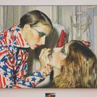 Illustration: Eine Person in USA-Flaggenjacke schminkt eine andere in einem Raum mit Fliesen und Vorhängen.