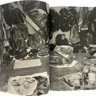 Keine erkennbaren Texte. Ein Mann sitzt in einem Atelier, umgeben von großen Stoff- oder Papierelementen an Wänden und Boden.