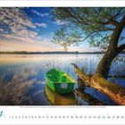 Ein grünes Boot am Wasser, großer Baum, blauer Himmel mit Wolken. Monatskalender April darunter.