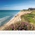 Küstenlandschaft bei Lønstrup, Region Nordjylland, Dänemark. Ein Haus steht auf hohen Klippen, davor violette Blumen und grünes Gras.