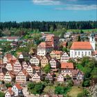 Es gibt keine sichtbaren Texte. Ein Dorf mit Fachwerkhäusern unter blauem Himmel, ein Kirchturm ist ebenfalls zu sehen.