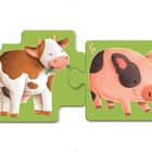 Zwei Puzzleteile mit Tieren: Eine glückliche Kuh und ein fröhliches Schwein auf grünem Hintergrund.