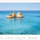 Kalenderblatt mit April-Daten: Zwei Felsen im klaren, blauen Meer, ein Mensch steht auf einem Paddelbrett.