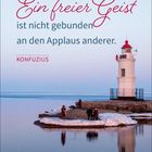 Text: „Ein freier Geist ist nicht gebunden an den Applaus anderer. KONFUZIUS“. Ein Leuchtturm am Meer, winterlich.