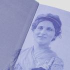 Keine sichtbaren Texte. Eine lächelnde Frau in Vintage-Kleidung und Hut ist abgebildet, in bläulichen Tönen gehalten.