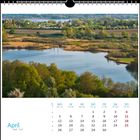 "April" und der April-Kalender. Landschaft mit See, Bäumen und kleinem Dorf am Horizont.