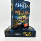 „WELLEN GRAB“ von Stefan Ahnhem. Zwei Bücher, eines aufrecht, eines liegend, mit Landschaftsmotiv.