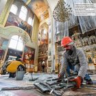 Text beschreibt Innenraum der Pokrova-Kathedrale nach Raketeneinschlag. Arbeiter räumen Trümmer, dekorative Kirchenmalereien.
