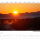 Aprilkalender mit Sonnenaufgang über bewaldeten Hügeln, Himmel in Orange und Gelb, Sonnenaufgang auf der Kaiserkrone.