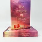 Zwei Bücher mit dem Titel "the weight of falling in love" von Sarah Stankewitz, rosa Himmel und Stadtbild im Hintergrund.