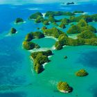 Keine Texte sichtbar. Mehrere grüne, mit Bäumen bedeckte Inseln in klarem, blauem Wasser aus der Vogelperspektive.