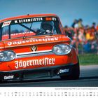 "W. Bergmeister", "Jägermeister", "Castrol" auf einem roten Rennwagen bei einem Rennen. Im Hintergrund Zuschauer.