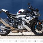Text: "M", "BMW", "Brose", "April". Ein modernes Motorrad vor einer blauen Wand. Darunter Kalendertage im April.