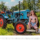 April. Alte Traktor mit der Nummer 6. Frau kniet, trägt Shorts, hält eine Kettensäge neben sich auf Gras.