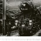 Text: "H 02 1001", "N 10", "April". Eine alte Dampflokomotive in einer Halle, ein Mann steht davor.