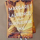 Text: "Margaret Laurence, Roman, Glücklichere Tage, mit einem Nachwort von Helene Bukowski, Eisele." 

Ein Buch cover mit herbstlichem Blättermuster.