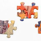 Drei bunte Puzzlestücke zeigen Teile von Gesichtern und einem skelettartigen Kopf in kräftigen Farben.