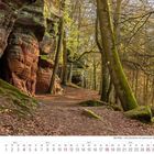 Kalenderseite April 2027; Waldweg an roten Sandsteinfelsen, eingerahmt von grünen, moosbedeckten Bäumen in weichem Licht.