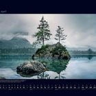 04 April. Ein See mit einem bewaldeten Felsen, Nebel und Bergen im Hintergrund. Kalenderdarstellung.