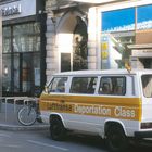 Texte: "Das Neue Europa", "Generali Foundation", "Lufttransa Deportation Class".  

Ein weiß-gelber Minibus steht auf der Straße.