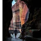 Unten rechts steht die Zahl 49. Menschen gehen durch einen dunklen Tunnel und betreten einen sonnigen, farbigen Felsenbereich.