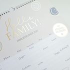 "Hello Family! FAMILIENPLANER 2027" mit Spalten Mama, Papa, Hannah, Mia, Ben; Aktivitäten wie Klavier, Joggen. Sticker: "MIT ADVENTSKALENDER".