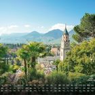 "Blick nach Meran 4" zeigt eine malerische Landschaft mit Kirchturm, üppigem Grün, Palmen und Bergen im Hintergrund.