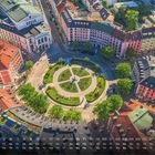 „Gärtnerplatz 5“ unten rechts. Kalenderantordnung darunter. Kreisförmiger Platz mit Bäumen umgeben von bunten Gebäuden.