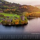"Urquhart Castle bei Loch Ness 4" zeigt eine Burgruine an einem See, umgeben von herbstlichen Bäumen und Hügeln.