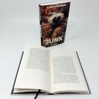 Ein aufgeschlagenes Buch mit schwarzen Lesebändchen. Dahinter steht ein Buch mit dem Titel "JUNK" von Ilona Hartmann.