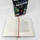 Der Titel auf dem Buchcover lautet "Patrick Ryan BUCKEYE". Ein Buch mit schwarzem Einband zeigt einen Mann unter einem Baum.