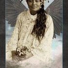 Im unteren Bereich steht "FRIEDEN". Eine Frau trägt Flügel, einen Blumenkranz und ein weißes Kleid, sie hält Blumen.