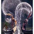 Der Text zeigt: "Fischer beim Reinigen ihrer Netze im Fluss Nhu Y, Vietnam." Darunter zwei Fischer, die Wasser spritzen.