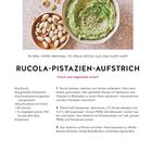 Rucola-Pistazien-Aufstrich Rezept und Bild eines grünen Aufstrichs in einer Schale und Pistazien auf einem Teller.