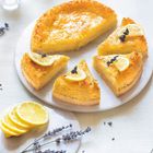 Kuchenstücke mit Zitronenscheiben und Lavendel dekoriert auf weißem Teller. Daneben Zitronenscheiben und Lavendelzweige.