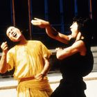 Zwei Männer kämpfen: Einer trägt Gelb, der andere Schwarz. Ihr Gesichtsausdruck zeigt Intensität und Bewegung.