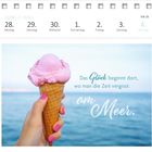 Das Zitat: "Das Glück beginnt dort, wo man die Zeit vergisst: am Meer." zeigt ein Eis in einer Hand vor dem Meer.