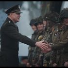 Ich kann keine detaillierten Texte im Bild erkennen. Ein Offizier gibt Soldaten in Uniform die Hand.