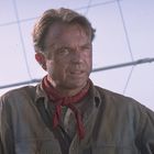 Keine erkennbaren Texte. Ein Mann mit braunen Haaren trägt ein rotes Halstuch und Hemd. Hintergrund: blauer Himmel.