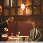 Ein Mann im Anzug spricht energisch in einem Restaurant. Ein zweiter Mann sitzt im Hintergrund.