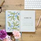 FEBRUAR, Kalenderseite mit blauen Blumen und grünen Blättern, daneben Tastatur, Stift und Blumen.