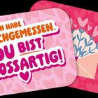 „Ich habe nachgemessen. Du bist großartig!“ steht auf einem rosa Hintergrund mit Herzchenmuster. Daneben ein Umschlag mit Blumen.