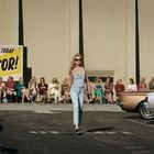 Ein großes Schild sagt: "OPEN CASTING TODAY SHOW US YOUR X FACTOR!" Frauen sitzen in einer Reihe, eine läuft vorne.