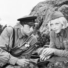 Ich kann die Personen nicht identifizieren. Zwei uniformierte Menschen unterhalten sich in einer felsigen Landschaft.