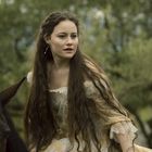 Keine Texte sichtbar. Eine Frau mit langen Haaren reitet auf einem Pferd, trägt ein historisches Kleid, grüner Hintergrund.