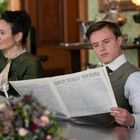 „Lloyds Weekly Newspaper“ steht auf einer Zeitung, die ein junger Mann liest. Eine Frau sitzt daneben. Beide sind elegant gekleidet.