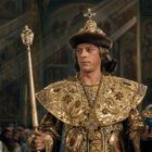 Ein prunkvolles kaiserliches Gewand, mit Gold und Edelsteinen verziert. Der Mann hält Zepter und Reichsapfel.
